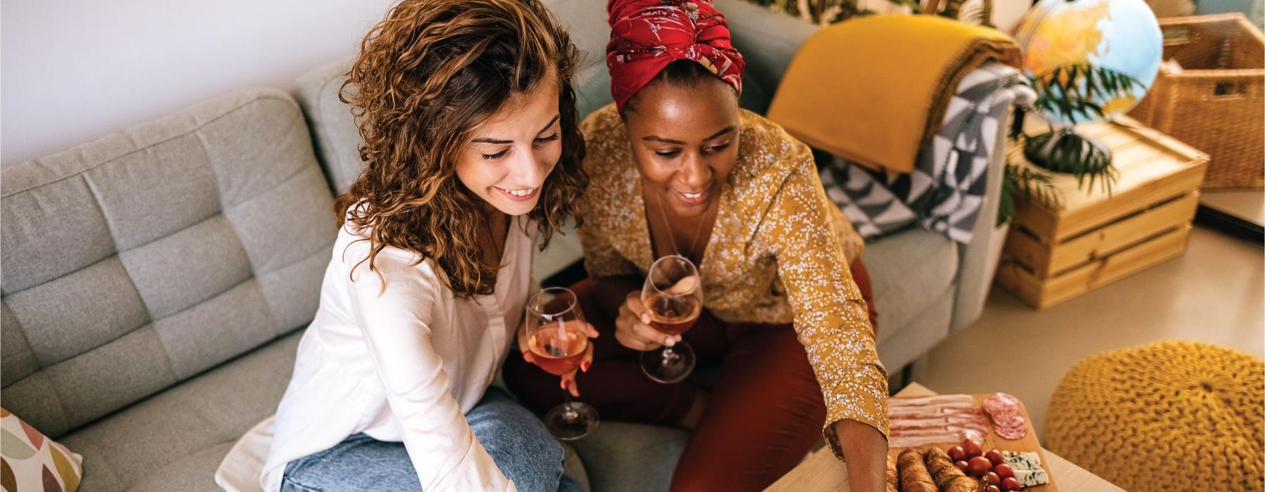 two women sitting on a couch with a laptop