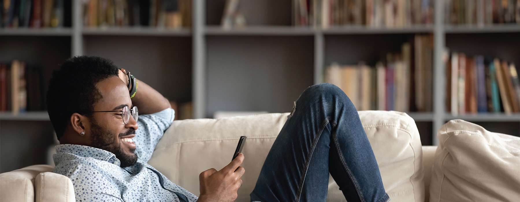 a man sitting on a couch smiling at his phone